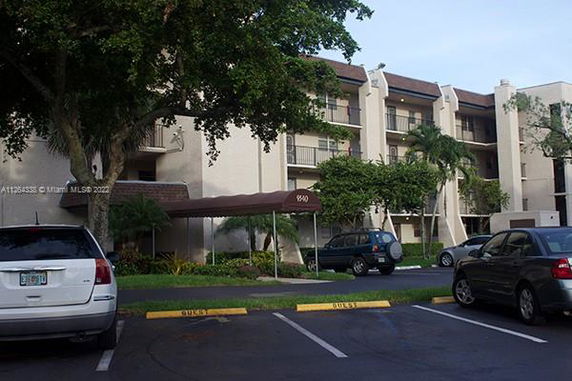 Parking area in front of a multi-story residential building with balconies.