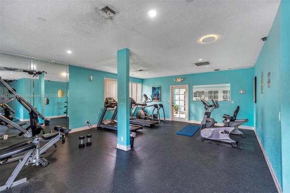 Indoor gym area with exercise equipment including treadmills and weights.