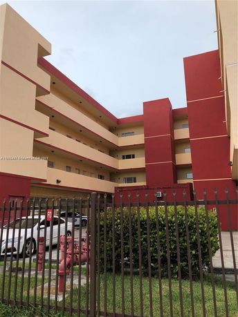 Front view of a multi-story building with red and beige facade.