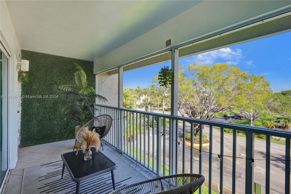 Balcony view overlooking trees and a street area.