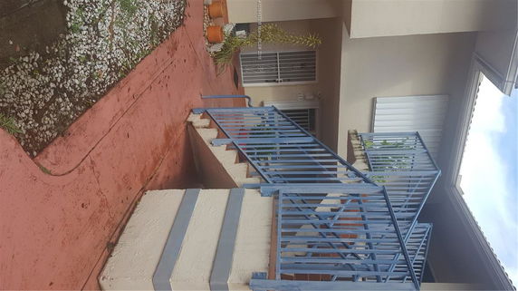 Front view of a house with a blue metal railing and stairway.