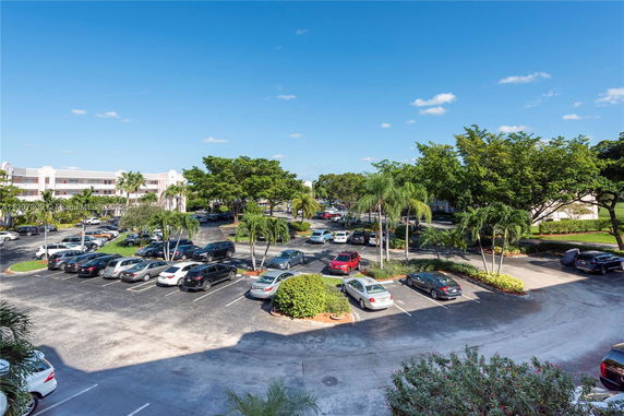 Outdoor parking area with multiple cars and surrounding trees.