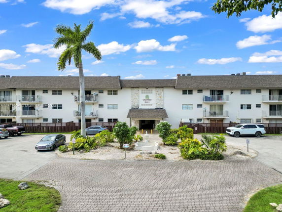 Front view of a multi-story residential building with balconies and parking area.