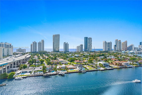 Panoramic view of a coastal city skyline with high-rise buildings and waterfront homes.