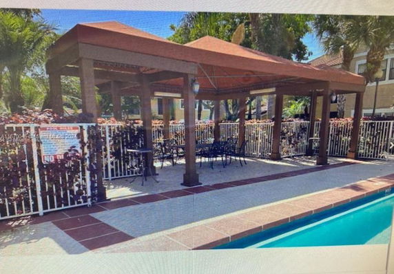 Outdoor swimming pool area with a pergola and seating.