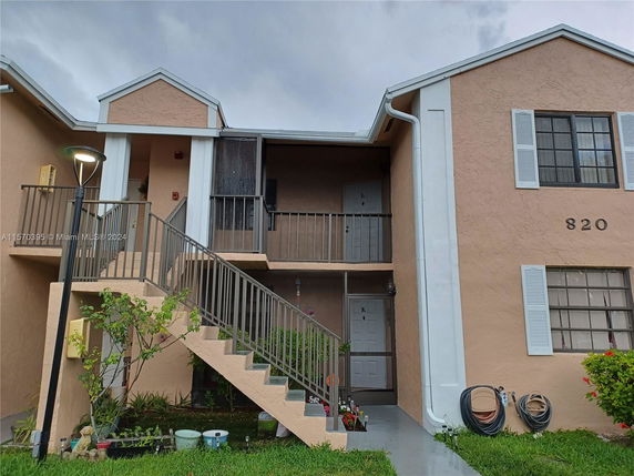 Front view of a two-story residential building with exterior stairs and numbered doors.