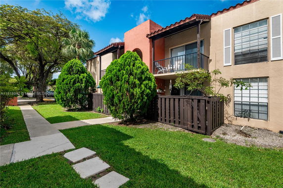Front view of a two-story residential building with balconies and a fenced patio.