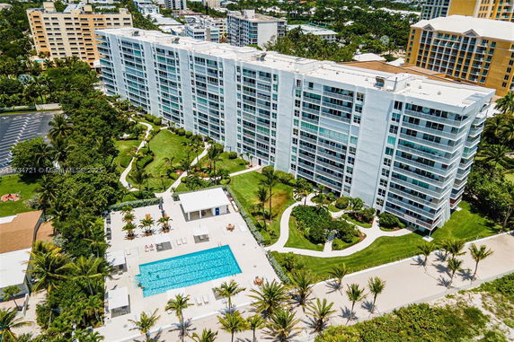 Aerial view of a multi-story building with a swimming pool and landscaped grounds.