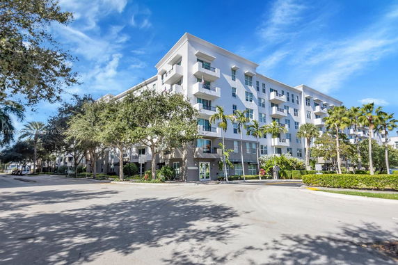 Front view of a multi-story apartment building with balconies and large windows.