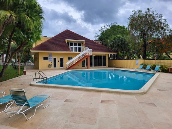 View of a swimming pool area with a small building adjacent to it.