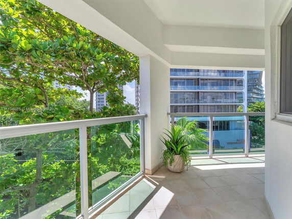 Balcony view overlooking modern buildings and lush greenery.