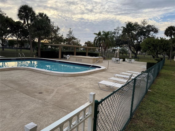 Outdoor swimming pool area with lounge chairs and surrounding greenery.