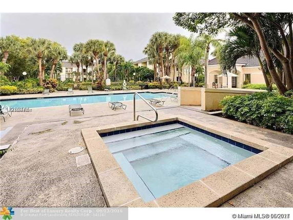 Outdoor swimming pool area with surrounding palm trees and building structures.