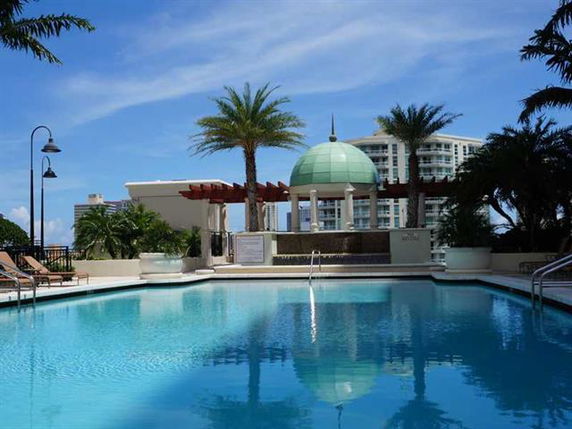 Outdoor swimming pool with a dome structure and palm trees in the background.