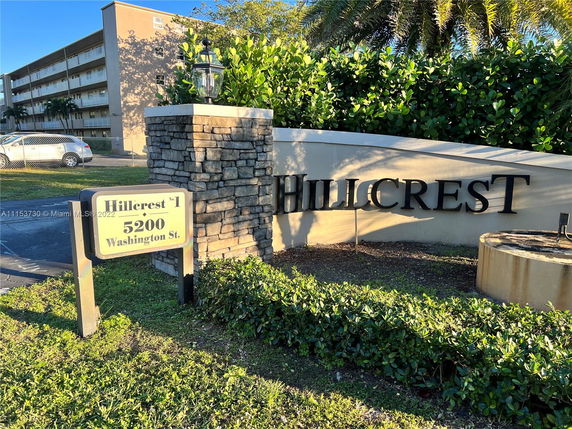 Front view of a multi-story residential building with a prominent sign reading 'Hillcrest' and address details.