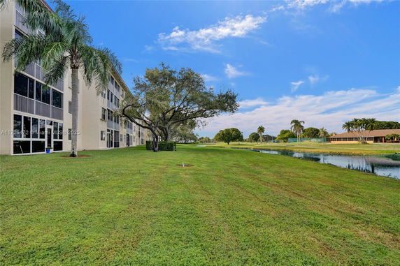 View of a building with large windows and a landscaped area with trees and grass.