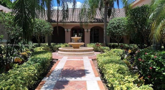 Front view of a house with a fountain and paved walkway.