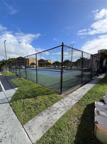 Outdoor fenced tennis court with a clear blue sky.
