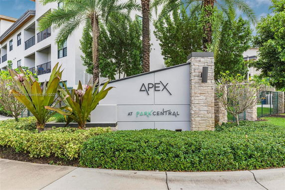 Front view of a modern multi-story building alongside its entrance sign.