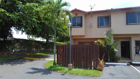 Front view of a two-story house with a brown fence and a satellite dish.