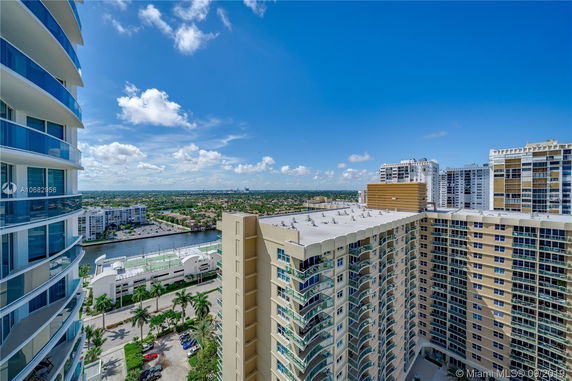 View of multiple high-rise buildings and surrounding landscape under a clear blue sky.