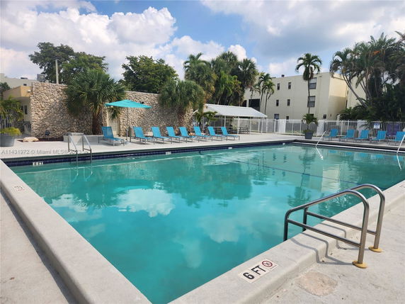 Outdoor swimming pool with lounge chairs and stone wall.