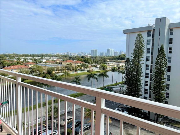 Balcony view overlooking residential area with buildings and water feature.
