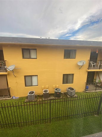 Side view of a two-story apartment building with air conditioning units and satellite dishes.