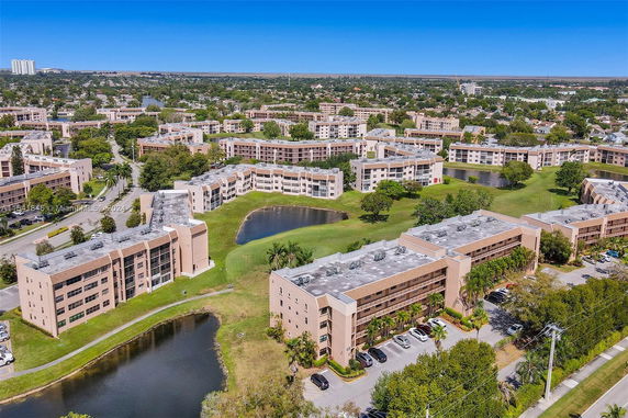 Aerial view of multiple residential buildings surrounded by green areas and ponds.