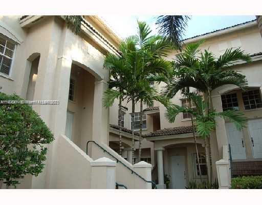 Front view of a multi-story building with arched entrances and palm trees.