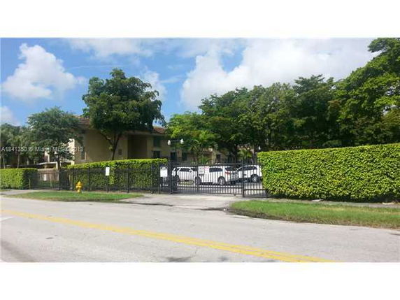 Front view of a two-story building with gated entrance and surrounding trees.