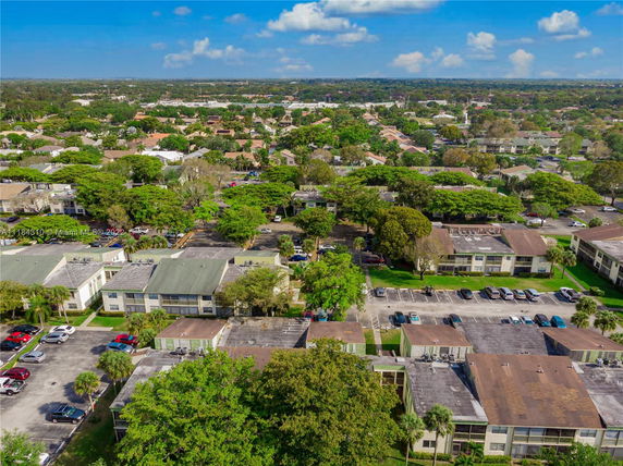 Aerial view of residential buildings with parking areas and surrounding greenery.
