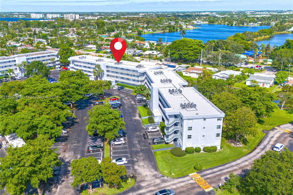 Aerial view of a multi-story residential building with surrounding neighborhood and lake.