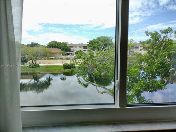 View from a window overlooking a pond and residential buildings.