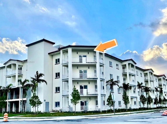 Front view of a multi-story residential building with balconies and a flat roof.