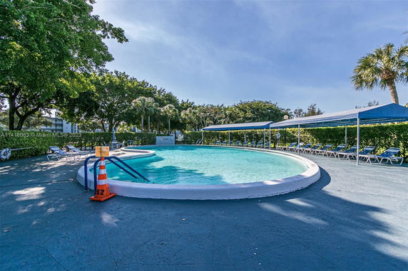 Outdoor swimming pool with surrounding lounge chairs and umbrellas.