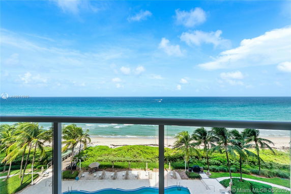 Panoramic view of the ocean from a balcony overlooking a pool and beach.