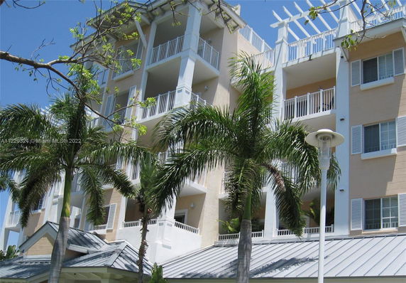 Front view of a multi-story building with balconies and palm trees.