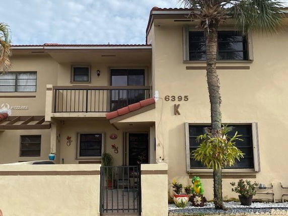 Front view of a two-story house with a balcony and a small garden.