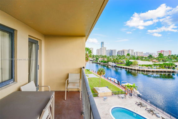 View from a balcony overlooking a canal, surrounding buildings, and palm trees.
