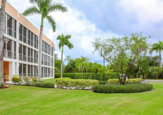 Front view of a multi-story building with large windows and a landscaped lawn.