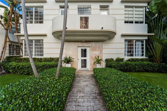 Front view of a two-story house with a rounded balcony and symmetrical windows.