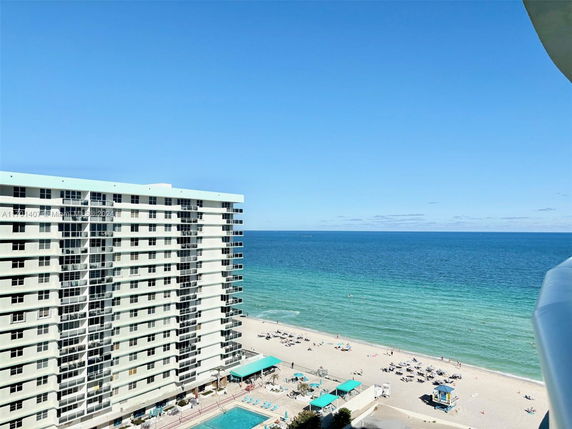 View of a multi-story beachfront building with balconies overlooking the ocean.