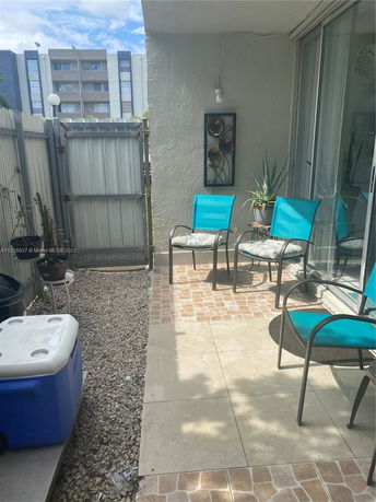Outdoor patio area with chairs and a small table, adjacent to a building with glass doors.