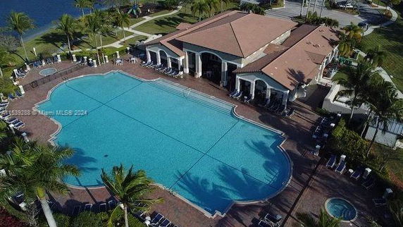 Aerial view of a large swimming pool adjacent to a building with a terracotta roof.