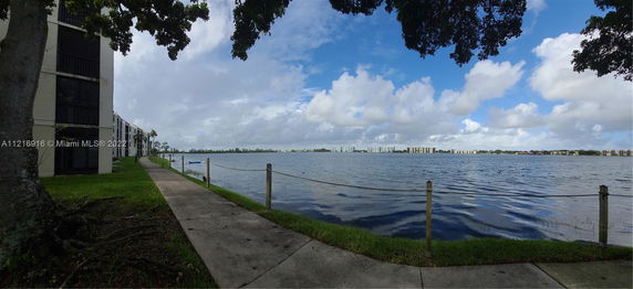 View of a waterfront scene with a building on the left and water extending towards the horizon.