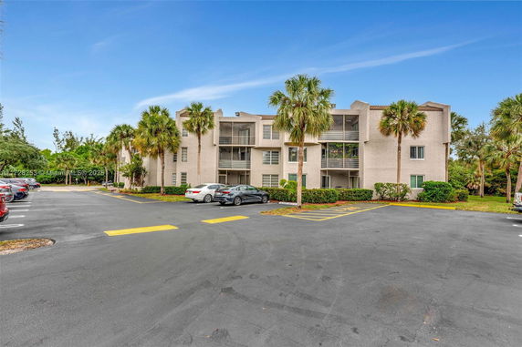 Front view of a multi-story building with balconies and parking area.