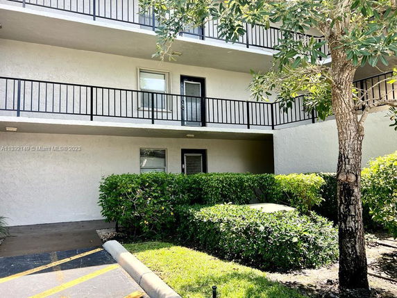 Outdoor parking area in front of a multi-story building with balconies.