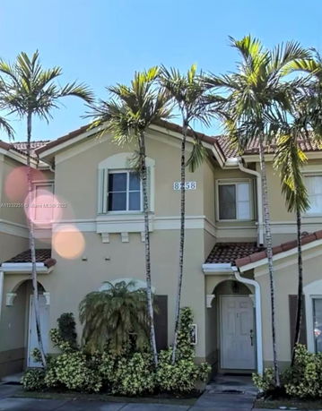 Front view of a two-story house with palm trees.