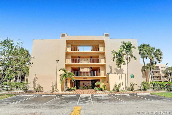 Front view of a multi-story building with balconies and palm trees in front.